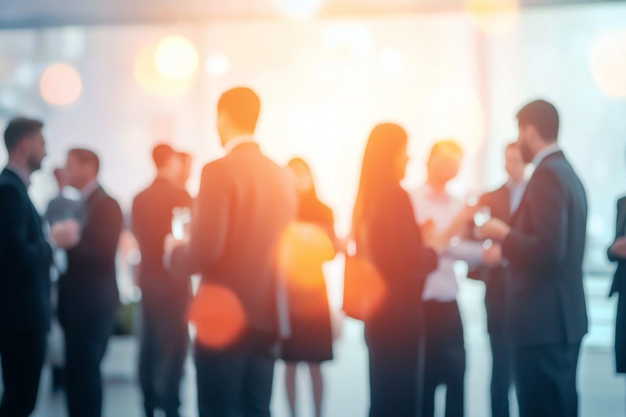 A vibrant networking event with business professionals engaging in conversation, blurred figures creating a sense of motion and activity