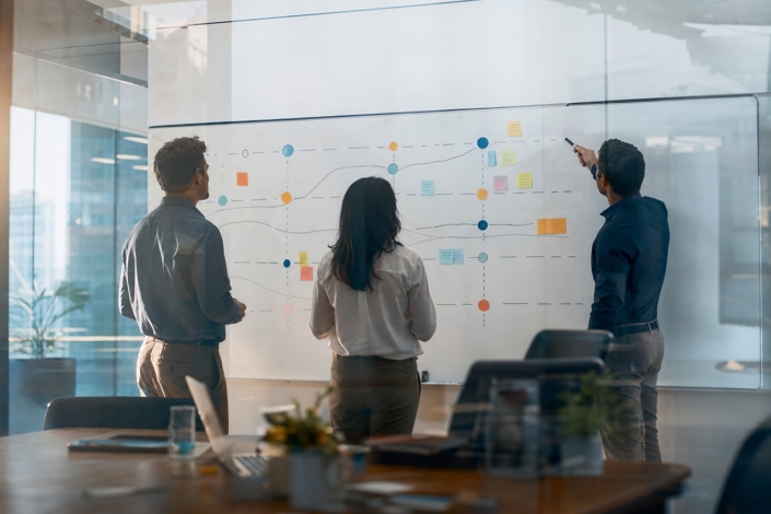 Business team mapping abstract strategy roadmap on large office whiteboard